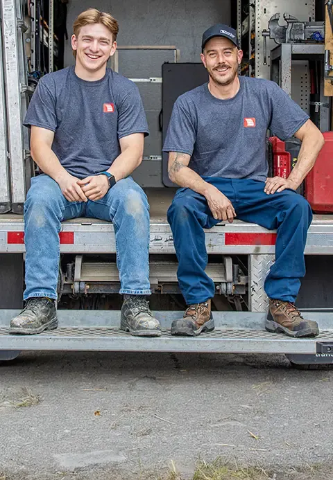 Deux techniciens de Portes Gignac assis à l'arrière de leur camion de service