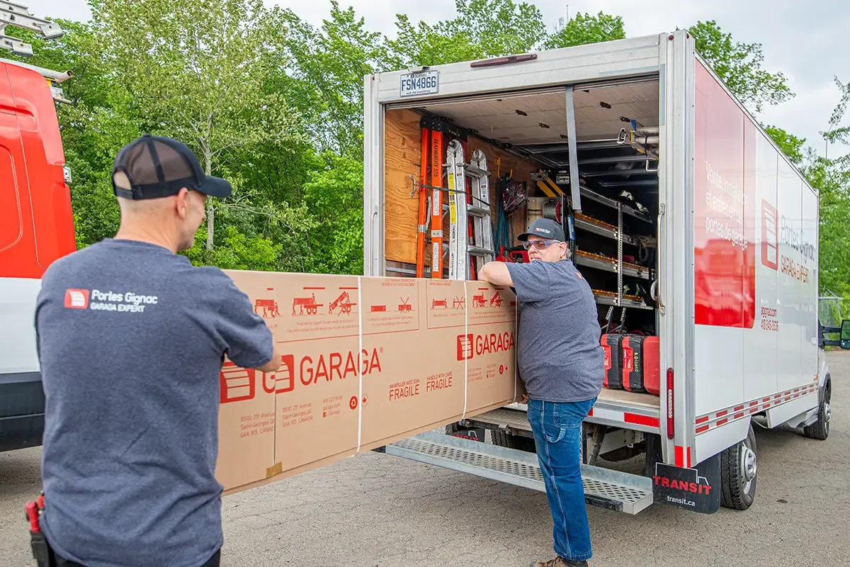 Installateurs avec porte de garage dans les mains devant leur camion